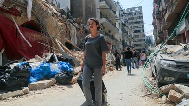 06.08.2020, Libanon, Beirut: Eine Anwohnerin steht vor ihrem Haus im Stadtviertel Achrafieh, das durch die Explosion im Hafen schwer beschädigt wurde. Der französische Präsident Macron sollte das Viertel besuchen, aber seine Tour musste abgesagt werd